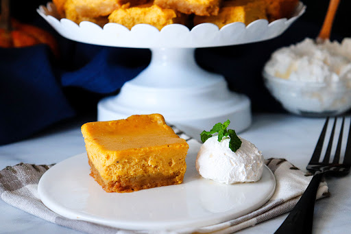 Pumpkin Cheesecake Bar on a plate with whipped cream.