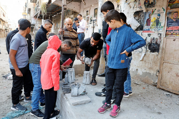 Palestinians look at the remains of a rocket following an air strike after Israeli forces raided Balata refugee camp in Nablus in the Israeli-occupied West Bank on November 18 2023.