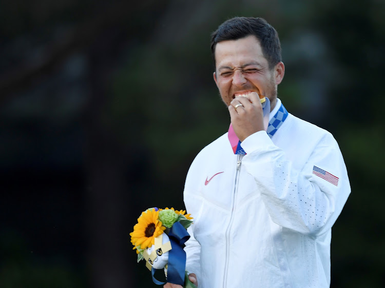 Gold medalist Xander Schauffele of the United States bites his medal.