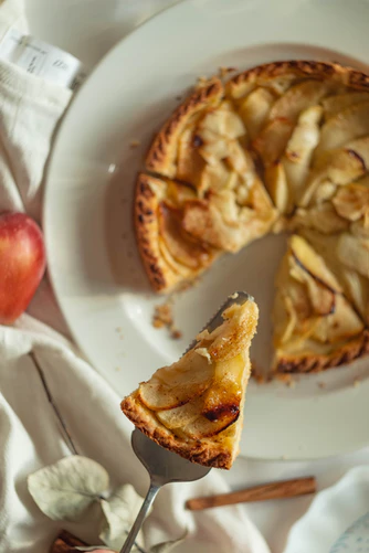 A photo of a slice of apple cake being lifted off a plate. 