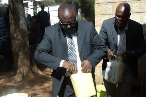 Armstrong Rono, director of the Uasin Gishu Alcoholic Drinks Control Board, inspects some of the illicit brew seized during police swoops in Eldoret, March 13, 2016. Photo/MWATHEWS NDANYI