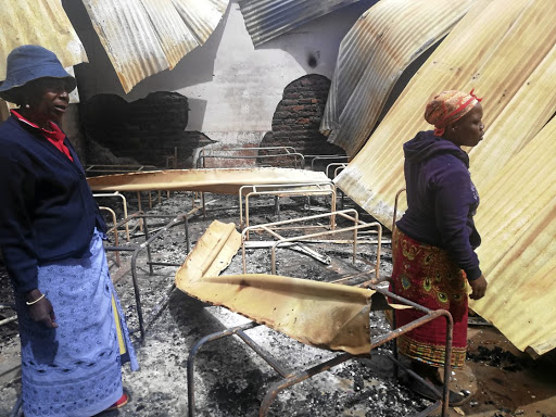 Residents walk through debris of burnt down Ratjeke Primary School in GaRatjeke village, near Giyani, in Limpopo./ PETER RAMOTHWALA