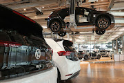 A ceiling conveyor carries a Volkswagen ID.3 electric car past others on the floor on the assembly line at the 