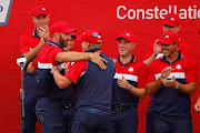 Team USA captain Steve Stricker is embraced by Team USA's Dustin Johnson on stage after winning the Ryder Cup.