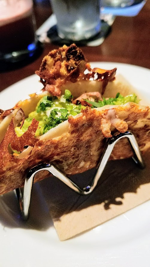 Yard House Portland Vampire Taco with carnitas, bacon chorizo, chipotle, cumin crema, guacamole, roasted garlic, cilantro. Vampire Style is a street taco wrapped in a grilled, crispy cheese-crusted flour tortilla shell