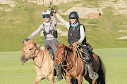 Willemien Jooste, in white hat, and Deirdre Griffith cross the finish line together as joint winners of the Mongol Derby.