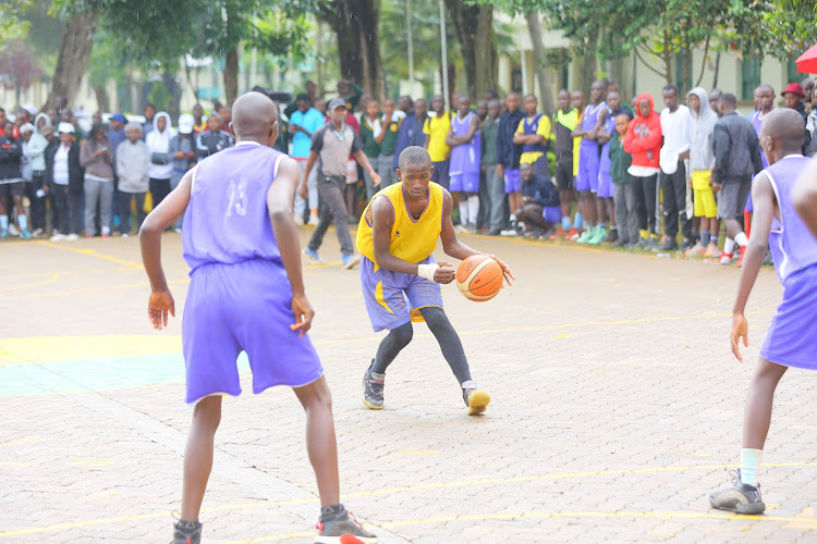 Gilbert Sangwera of Nyanchwa attepts to dribble past two Cardinal Otunga High School players during the Kisii County basketball final