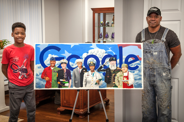 Un hombre y su hijo de pie junto a una impresión de un Doodle de Google que muestra a seis veteranos de diferentes ramas militares