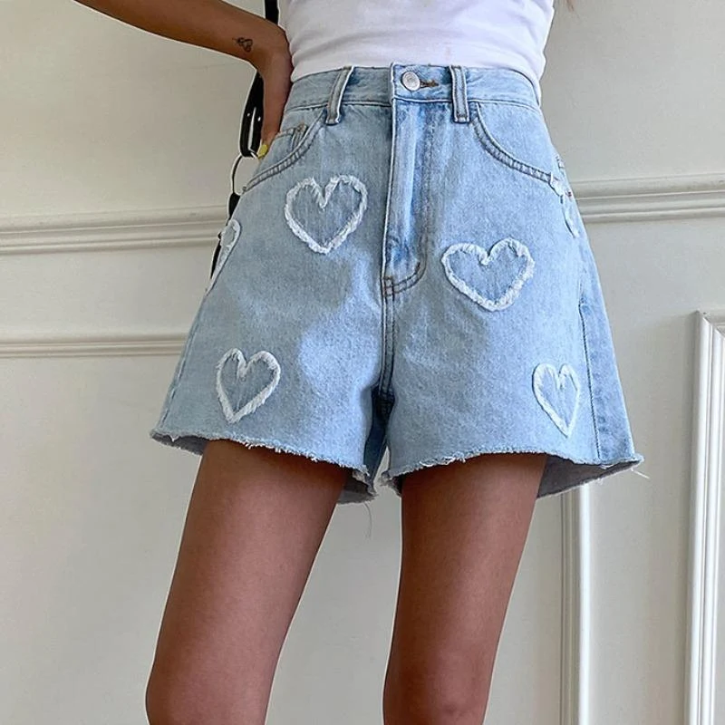 Shorts jeans de cintura alta com padrão de coração desfiado, cor clara e lavagem, perfeitos para looks leves e frescos no verão.