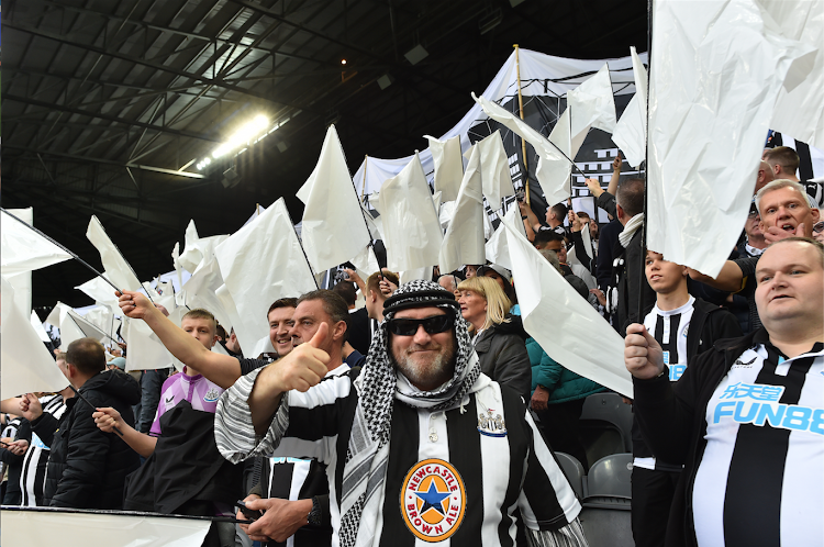 Newcastle United fans wave black and white flags and banners celebrating the club's recent take over by a Saudi-led consortium during a Premier League football match between Newcastle United and Tottenham Hotspur at St James' Park.