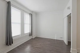 Bedroom with light walls and trim, window with curtains and blinds, wood-inspired flooring, and a white sliding door closet