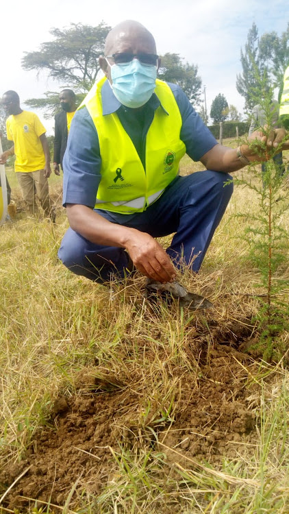 Rift Valley Institute of Science and Technology Principal, Daniel Mutai poses for a photo after planting a tree at the institution.