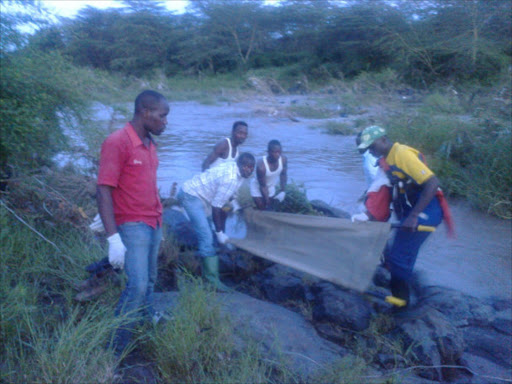 A photo of Jam City slum residents in Athi River and officers from Mavoko fire brigade retrieving bodies of three men