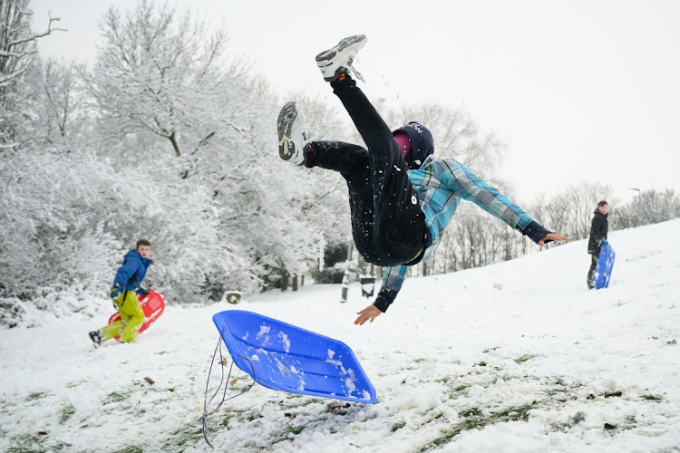 A man takes to the air after hitting a ramp while sledging in Alexandra Park on December 12 2022 in London. Snow and ice disrupted rail travel and closed schools in parts of southeast England on Monday.