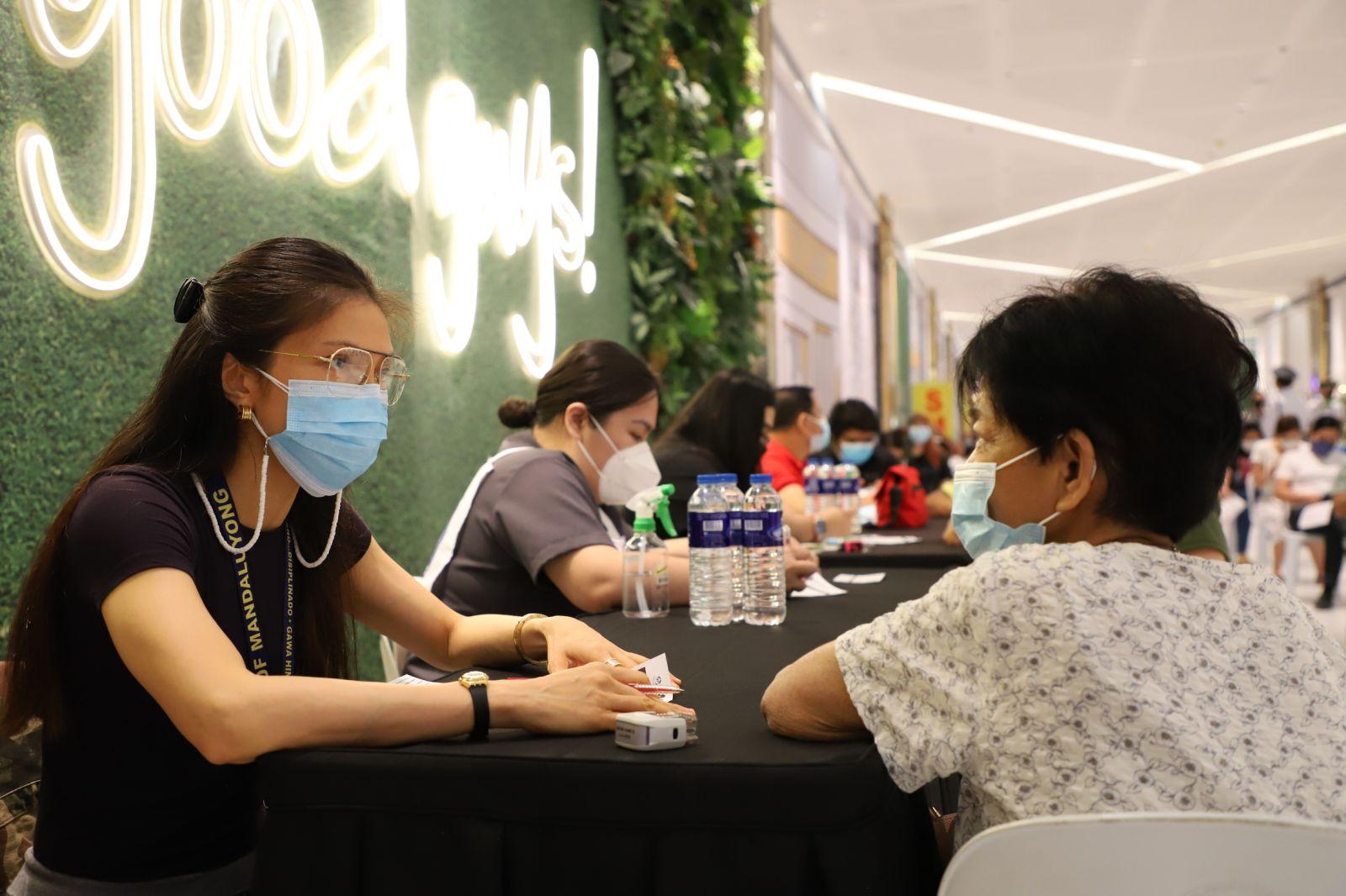 an elderly woman talking to a receptionist for SMDC Health and wellness caravan