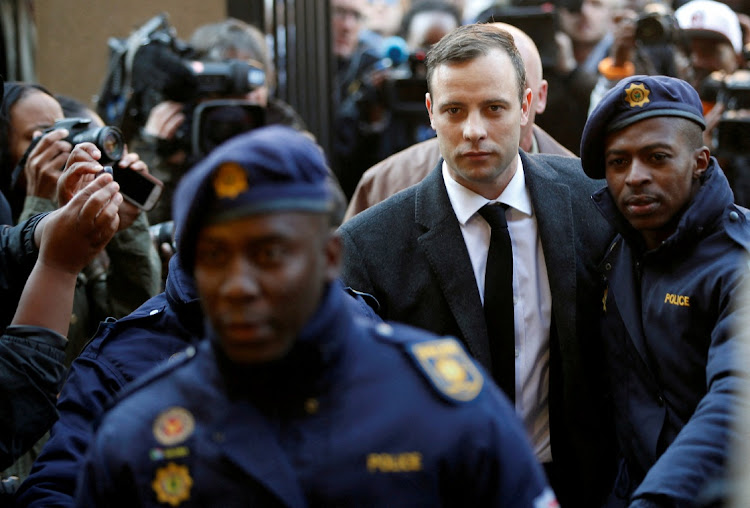 Oscar Pistorius is escorted by police officers as he arrives for his sentencing for the 2013 murder of his girlfriend Reeva Steenkamp, at North Gauteng High Court in Pretoria on July 6 2016. Pretorius was released from prison on parole on Friday