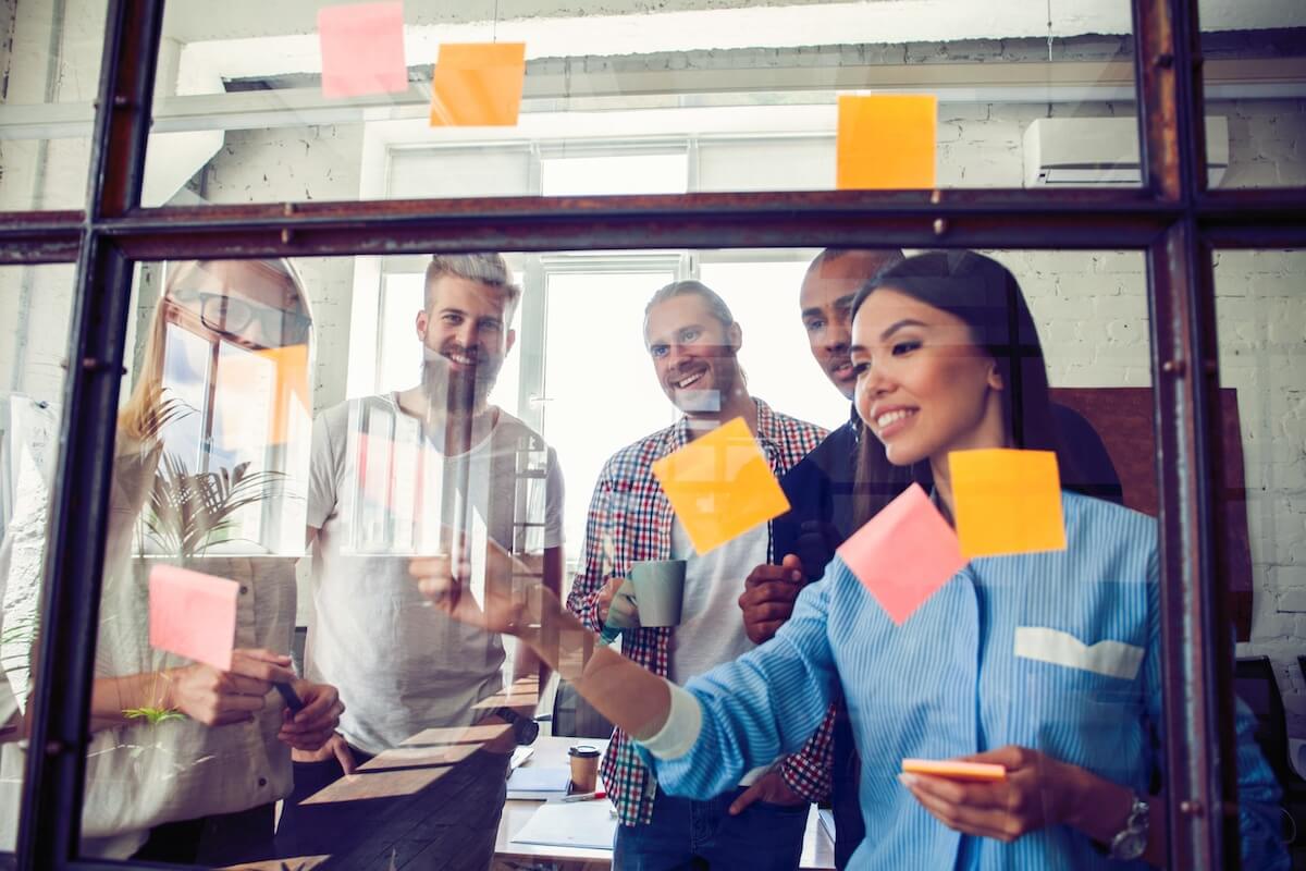 Team arranging sticky notes on a glass board