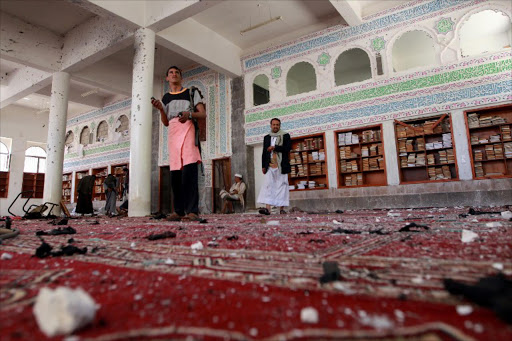 Yemeni armed men inspect the damage following a bomb explosion at the Badr mosque in southern Sanaa