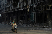 Cambodian police officers ride a motorcycle past the Grand Diamond City hotel-casino, as Thai and Cambodian rescuers struggle to extricate dozens of people feared trapped after a fire broke, killing at least 10 and injuring dozens in Poipet near Thailand border, Cambodia, December 29, 2022. 