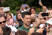  Novak Djokovic of Serbia stops his car to greet fans after posing with the Norman Brookes Challenge Cup after winning the 2023 Australian Open, on January 30, 2023 in Melbourne, Australia. 