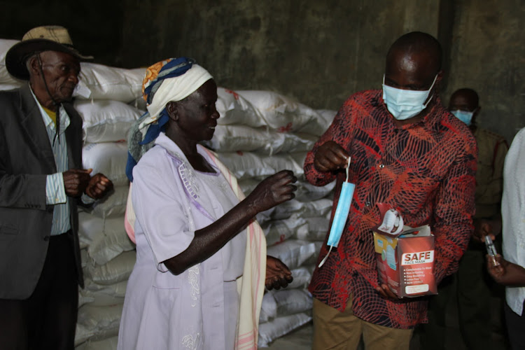 Minority leader and Suba South MP John Mbadi gives a face mask to some two elderly people at Magunga DCC offices in his constituency on May 2,2020