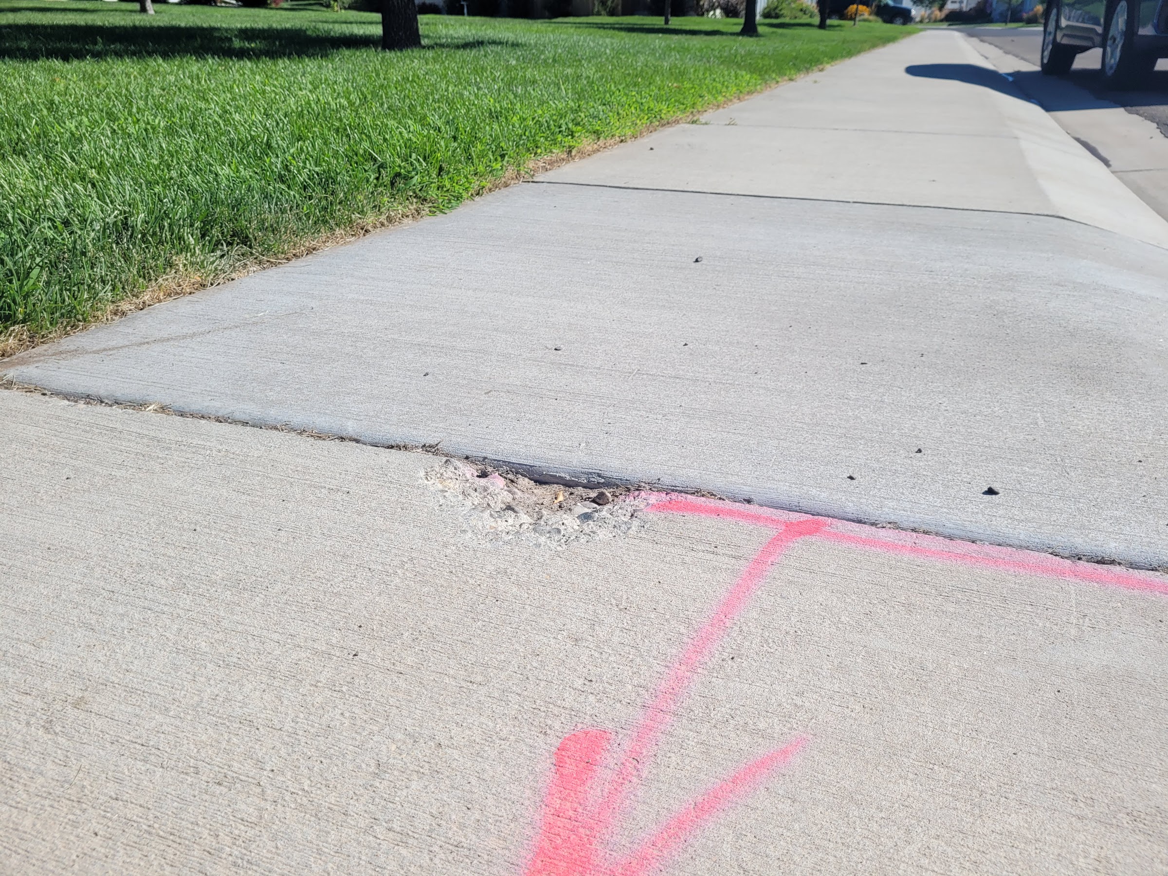 a cracked sidewalk with a pink arrow