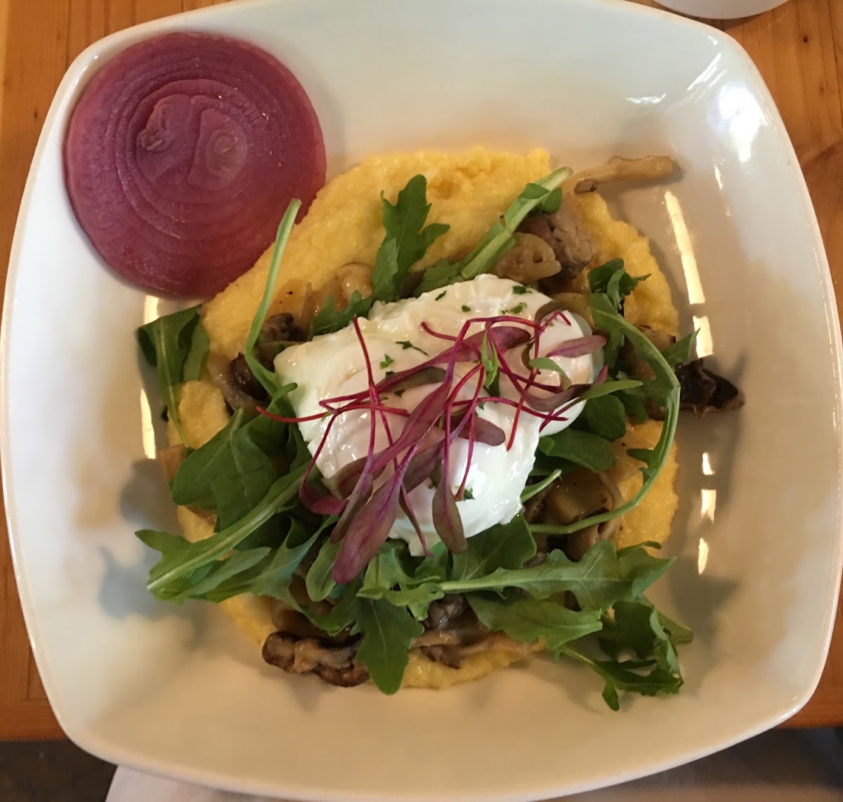 Creamy Polenta and Eggs. Poached eggs, caramelized onion, roasted mushrooms and garlic and arugula on polenta.