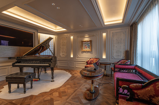 Living room with grand piano and red armchairs in this luxury property for sale in Minato City ($9,320,457)