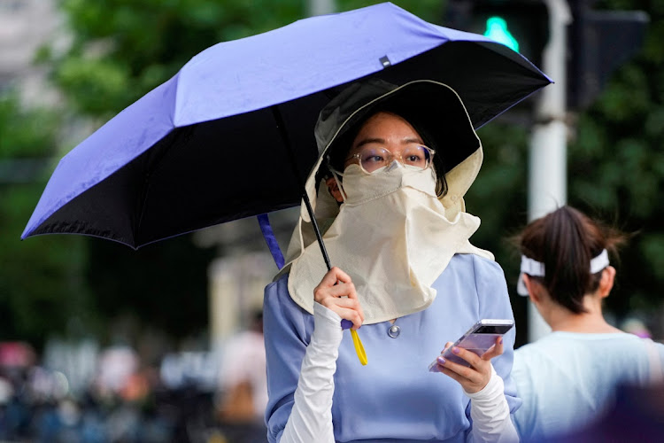 A woman walks on a street as she shields herself from the sun with a hat, mask and umbrella amid an alert for a heatwave in Shanghai, China July 4 2023. Picture: REUTERS