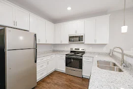 Kitchen with wood-inspired flooring, stainless steel appliances, and white cabinets with a double sink