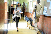 A student walks past a private security company guard and sniffer dogs checking for explosives in the corridors of Wits University. Safety of students needs to be a priority, the writer feels. 