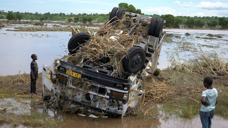 Locals look at a wreck washed away during tropical storm Ana on the flooded Shire river, an outlet of Lake Malawi at Thabwa village, in Chikwawa district, southern Malawi, on January 26 2022.