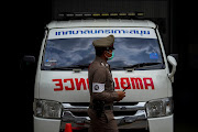 A police officer walks past an ambulance carrying the body of Australian cricket player Shane Warne outside the forensic laboratory of Surat Thani hospital, where Warne's body was transferred for autopsy, in Surat Thani province, Thailand, on March 6 2022. 