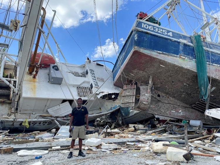 Ricky Moran stands in front of a shrimp boat, captained by him, and two other damaged boats, which were hit by Hurricane Ian at a Fort Myers Beach dock, Florida on October 5 2022. Picture: REUTERS/ROD NICKEL