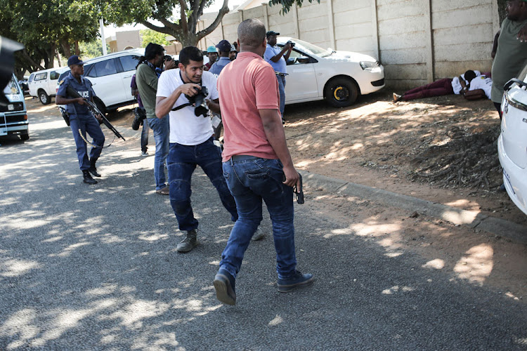 A plain-clothes policeman pulls his firearm while arresting pupils following the petrolbombing of a police car outside the school.