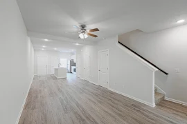 Open concept floorplan with light gray walls, wood inspired floor, white trim, doors, and cabinets, large kitchen island