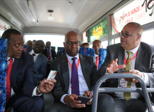 President Uhuru Kenyatta display his card for the new cashless payment system for public service vehicles at State House on November 5 as Safaricom CEO Bob Collymore and MOA Chairman Simon Kimutai looks on. Photo/PSCU