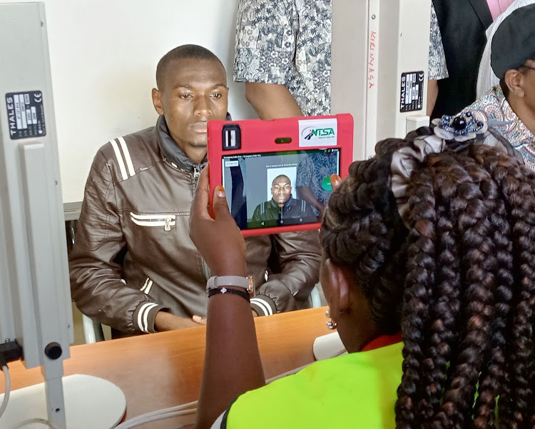 An NTSA offical take a passport photo of one of the riders who registered on Monday at the Kerugoya huduma center.