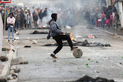 A protester blocks a street with stones and rubble in Msiphumelele, Cape Town, during the ongoing strike by taxi operators against traffic authorities. 