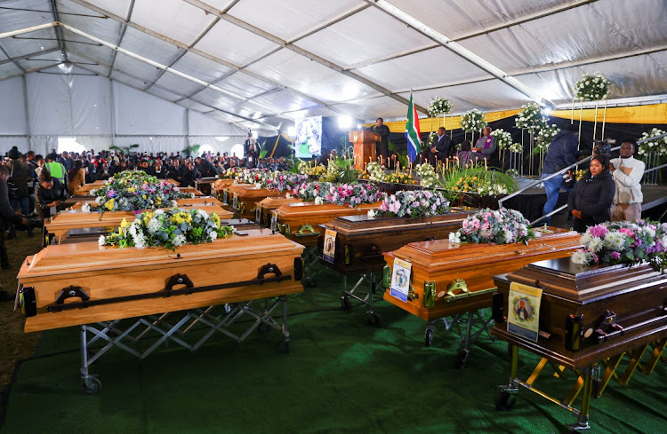 People gather near empty coffins ahead of the mass funeral for the victims of the East London tavern tragedy on July 6 2022.
