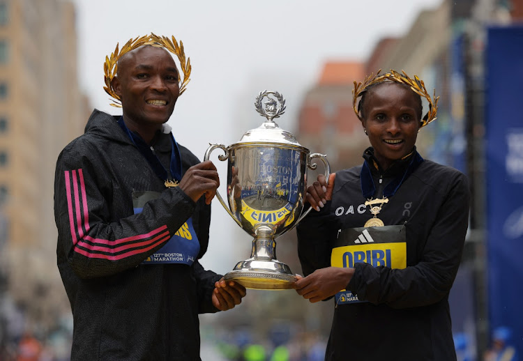 Kenya's Evans Chebet and Hellen Obiri pose with the trophy at the finish line after winning the elite men's and elite women's races of the 127th Boston Marathon in Boston, Massachusetts on April 17 2023.