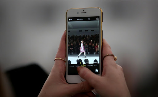 A guest takes a photograph on their iPhone at the Bora Aksu show during London Fashion Week Fall/Winter 2015/16 at Somerset House on February 20, 2015 in London, England.