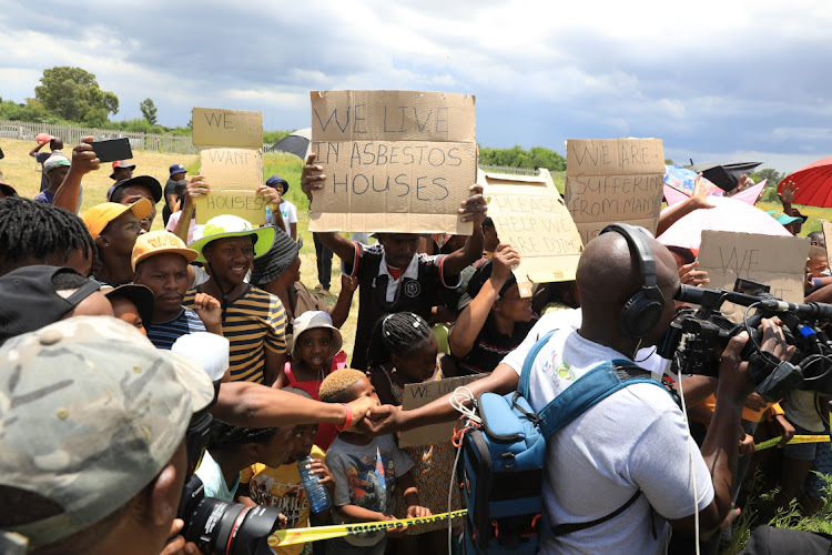 Maokeng residents, some holding placards demanding better service delivery, look on as President Cyril Ramaphosa attends the grave site of former ANC president Zaccheus Mahabane in the Free State before the party's 111th birthday celebrations on Sunday.