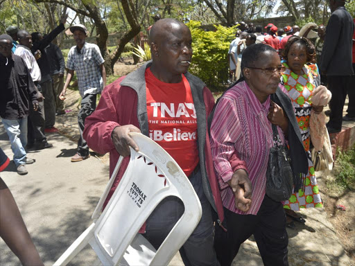 A woman is whisked away from the scene during the Nakuru Jubilee meeting that ended prematurely as rowdy youths stormed the meeting accusing one James Karemi for 'Hi-jacking' the Jubilee party Leadership./RITA DAMARY