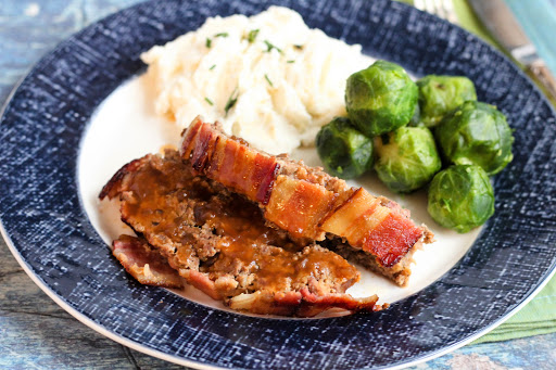 Two slices of Bacon Wrapped Salisbury Meatloaf with gravy on top.