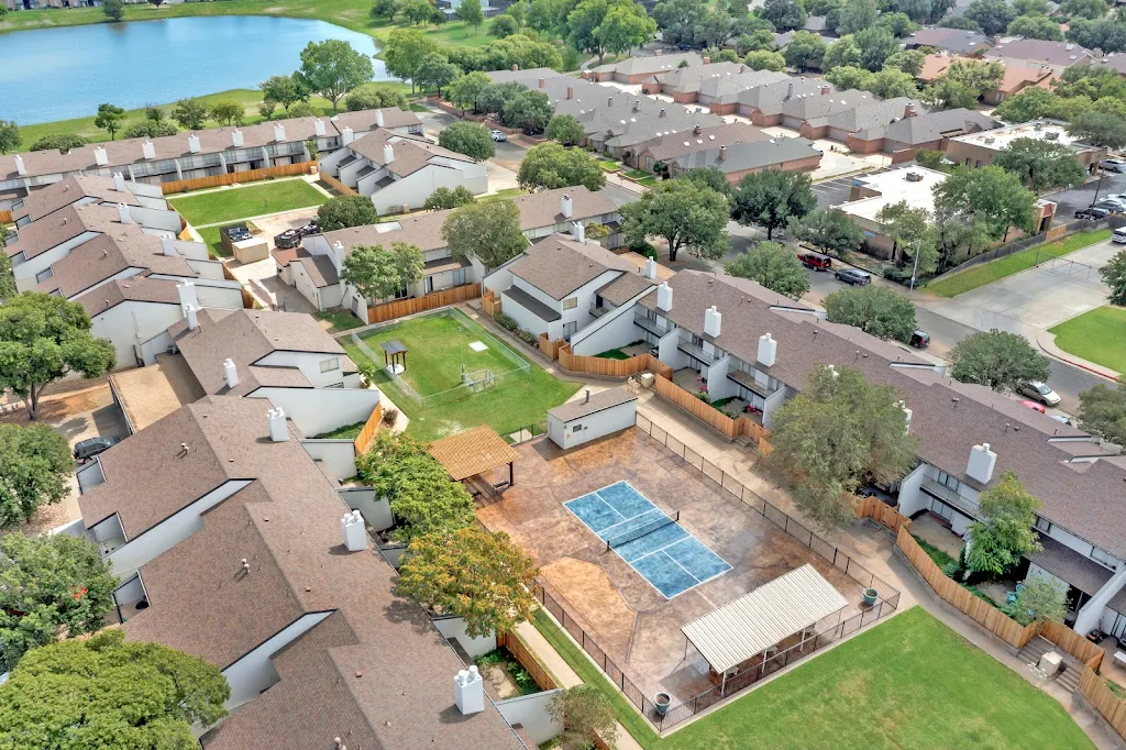 Aerial view of apartment community with tennis court and dog park in the middle