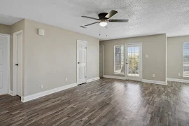 Living area with wood plank flooring, neutral walls, white trim, and a patio door with a window 