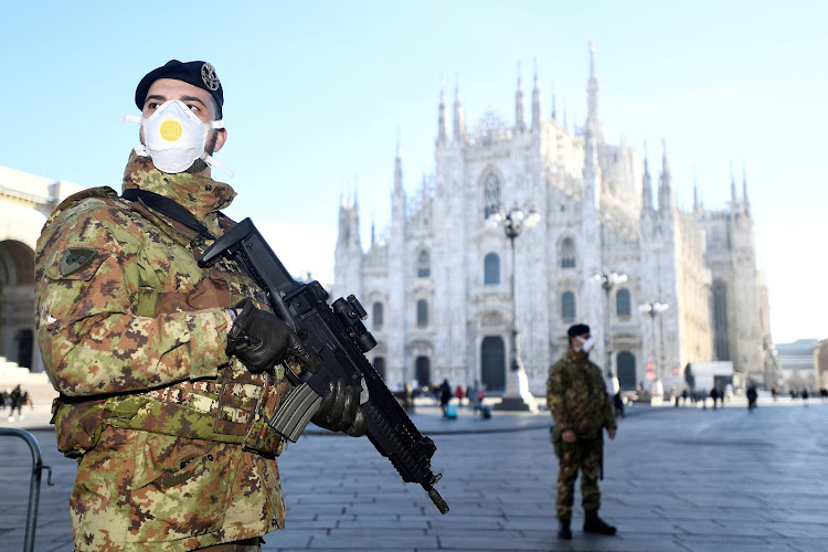 FILE PHOTO: Military officers wearing face masks stand outside Duomo cathedral, closed by authorities due to a coronavirus outbreak, in Milan, Italy February 24, 2020. REUTERS/Flavio Lo Scalzo/File Photo