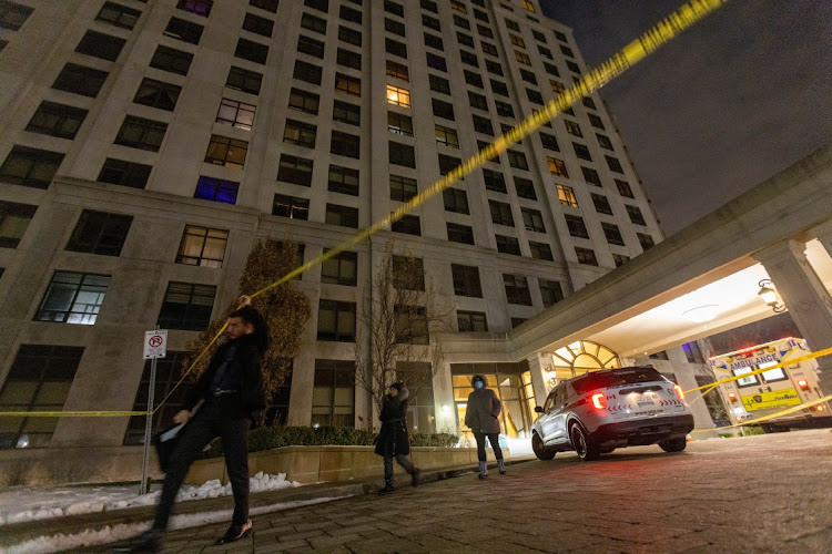 A person walks under the police line after a fatal mass shooting at a condominium building in the Toronto suburb of Vaughan in Ontario, Canada, on December 19 2022.