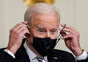 US President Joe Biden replaces his face mask after delivering remarks on the implementation of the American Rescue Plan in the State Dining Room at the White House in Washington, US, March 15, 2021. 